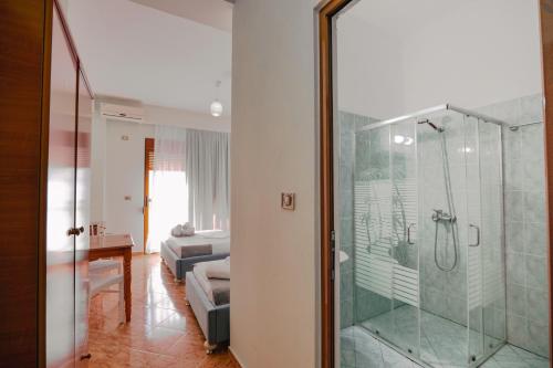 1 dormitorio y baño con ducha acristalada. en Hotel Panorama, en Himare