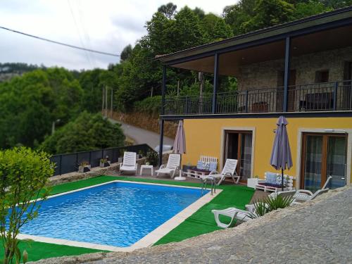a house with a swimming pool with chairs and umbrellas at Casa do Toucedo - Encanto da Natureza Caniçada / Gerês in Caniçada