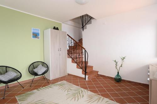 a living room with a staircase and two chairs at B&B Saracinello in Praia a Mare