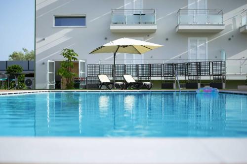 una piscina con 2 sillas y una sombrilla en Resort Policastro, en Policastro Bussentino