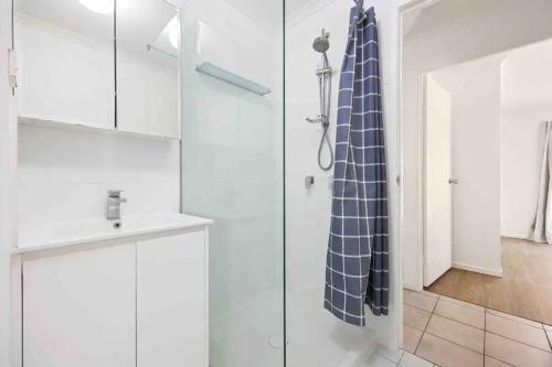 a bathroom with a shower with a sink and a blue shower curtain at Hervey Bay Shelly Beach Stay ,Pet Friendly 300m to beach in Torquay