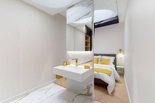 a white bathroom with a sink and a bed at Le petit Piron in Dijon