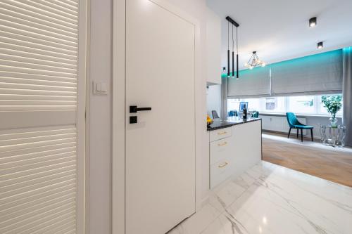 a kitchen with white cabinets and a dining room at LuxuryApartamentsIjordC in Katowice