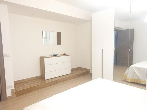 a white bedroom with a bed and a mirror at Nancy Casa vacanze in Nizza di Sicilia