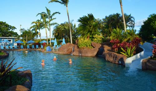 a pool at a resort with people in the water at KP40 1Br Poipu Corner Condo with AC, Steps to the Beach in Koloa