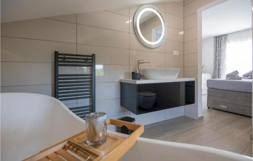 uma casa de banho com uma banheira, um lavatório e um espelho. em Awesome Home In Donji Vinjani With Kitchen em Topići