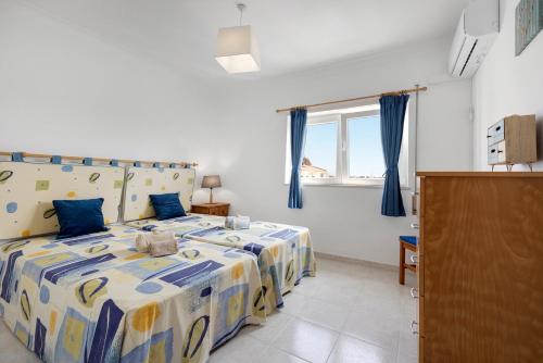 sypialnia z łóżkiem z niebieskimi zasłonami i oknem w obiekcie Pérola no Algarve w mieście Portimão