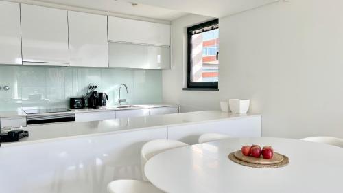 a white kitchen with a white table and chairs at Troia Garden View Apartment in Troia