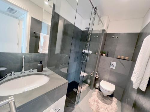 een badkamer met een wastafel, een toilet en een douche bij Troia Garden View Apartment in Troia