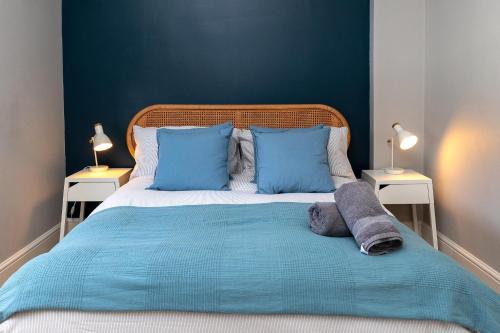 a large bed with blue pillows and two night stands at The Old Stables in Southampton