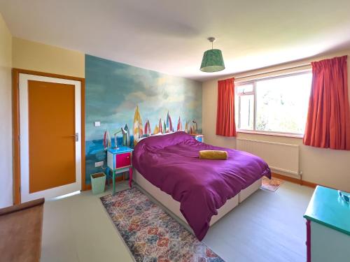 a bedroom with a purple bed and a painting on the wall at Aqua Cottage in Combe Martin