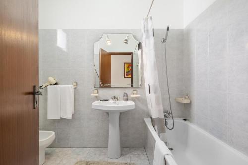 a white bathroom with a sink and a bath tub at Escapadinha do Sol by Homie in Pontinhas