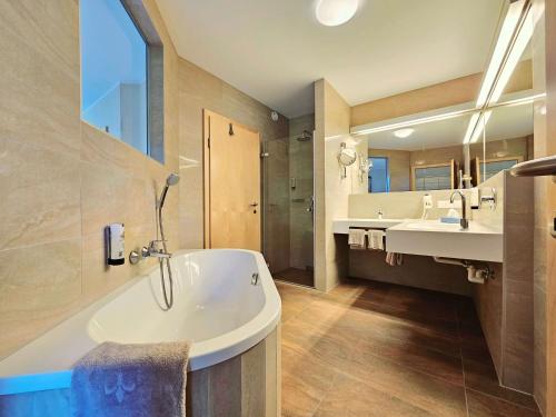 a large bathroom with two sinks and a tub at Familienhotel Trebesingerhof in Trebesing