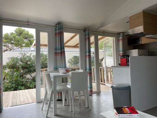 cocina con mesa blanca y sillas blancas en Mobil Home - Camping La Falaise en Narbonne