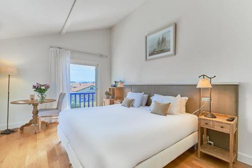 a bedroom with a large white bed and a table at Villa L'Arche in Bidart