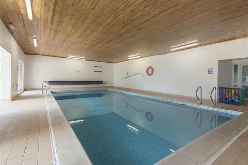 a large swimming pool with a wooden ceiling at Saddlers Cottage with indoor pool, tennis court and lots more Tenby area in Saint Florence