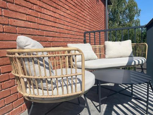 a patio with two chairs and a table and a brick wall at Apartament Jaskółki w Pilicach in Jastrzębia Góra