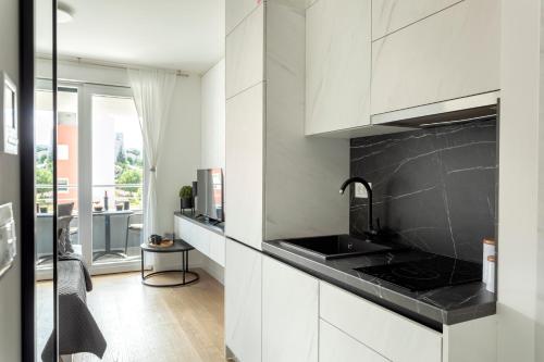 a kitchen with white cabinets and a black counter top at Apartman Elena in Split