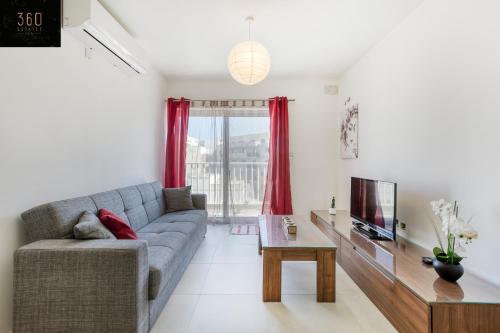 uma sala de estar com um sofá e uma televisão em Lovely 2BR home 2 mins away from the promenade by 360 Estates em St. Paul's Bay