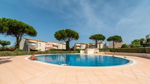 - une piscine dans une cour avec des arbres et des maisons dans l'établissement Port Lano - 3 - Appt lumineux 4-6 pers, au Cap d'Agde