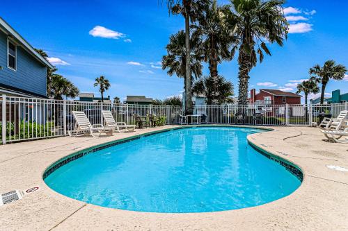 a swimming pool with chairs and a fence and palm trees at Unsearchable Colony V in Port Aransas