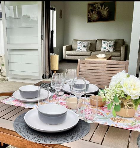 a table with plates and wine glasses on it at Perfect On The Park in Tauranga