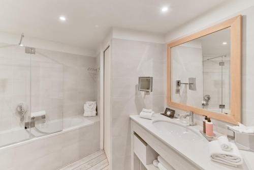 a white bathroom with a tub and a sink and a mirror at Villa L'Arche in Bidart