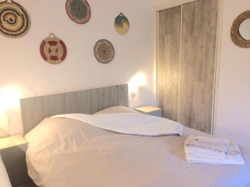 un letto bianco in una camera da letto con piatti appesi al muro di Au calme dans le centre avec terrasse et clim a Saint-Rémy-de-Provence