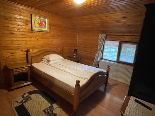 ein Schlafzimmer mit einem Bett in einer Holzhütte in der Unterkunft Pensiunea Liliana in Câmpulung Moldovenesc