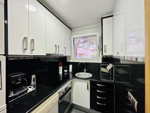 a kitchen with black and white cabinets and a sink at Paradis CostaBravaSi in Platja d'Aro