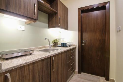 a kitchen with a sink and a wooden door at 46 Serviced Apartments in Amman