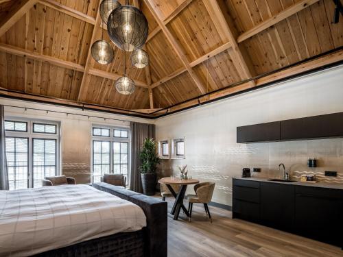 een slaapkamer met een bed en een tafel en een keuken bij Lindenhuys Logies in Sint-Oedenrode