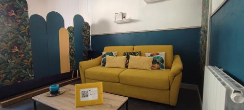 un divano giallo in una stanza con tavolo di Le Costa Rica - Grand appartement centre ville a Boulogne-sur-Mer