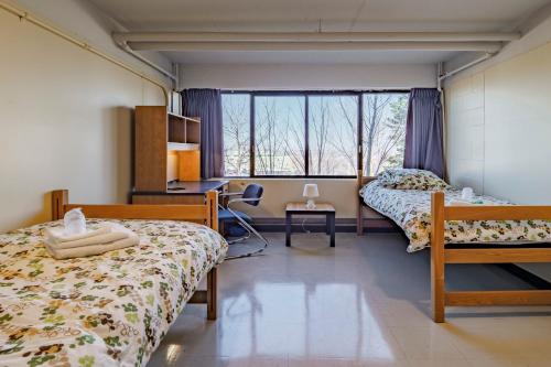 a bedroom with two beds and a desk and a window at Au Campus in Sherbrooke
