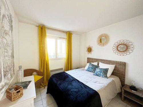 a bedroom with a bed and a window with yellow curtains at Bel appartement 3 pièces climatisé 400m des plages in Cavalaire-sur-Mer