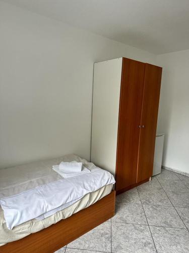 a bedroom with a bed and a wooden cabinet at Pension Seckbach in Frankfurt/Main
