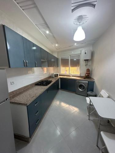 uma cozinha com armários azuis, uma mesa e um fogão em SAIDIA COSY FLAT em Saïdia