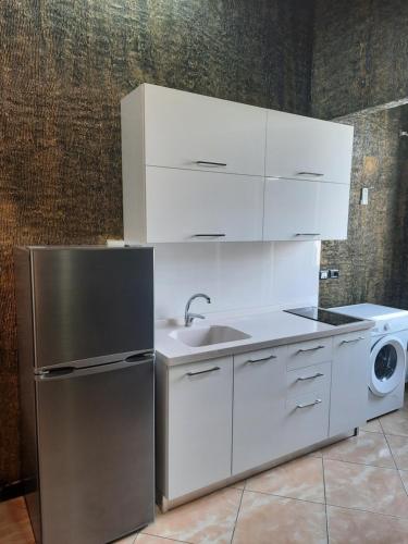 a kitchen with white cabinets and a sink and a refrigerator at VILA PUSHIMI REGIS in Velipojë