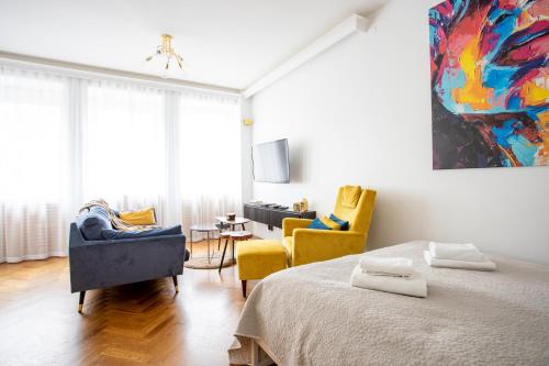 een slaapkamer met een bed en twee stoelen en een schilderij bij GA- Luxury Apartment-Top Location&Żurawia in Warschau