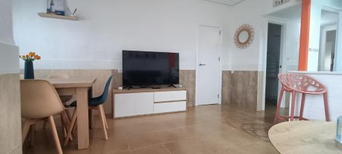 a living room with a television and a table with chairs at Mi Casita del Cabo in El Cabo de Gata