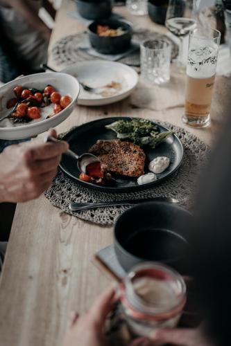 a table with plates of food and a person holding a spoon at Alpenappartements Cristall in Ehrwald