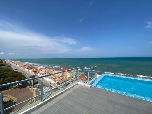a balcony with a swimming pool and the ocean at PISO-DEL-PLAYA in Guardamar del Segura