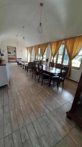 Un comedor con mesa y sillas y ventanas. en La Guarida Lobos, en Lobos