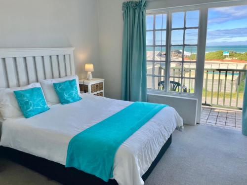 a bedroom with a bed with a view of the ocean at 26 Settler Sands Beachfront Accommodation Sea View in Port Alfred