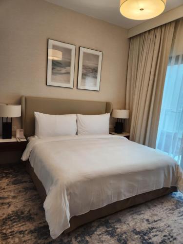 Address Beach Resort Fujairah - 2 bedroom apartment في الفجيرة: سرير أبيض كبير في غرفة الفندق مع نافذة
