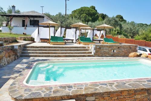 a swimming pool with chairs and a house at Katigiorgis Bungalow Villa & SPA in Agios Georgios
