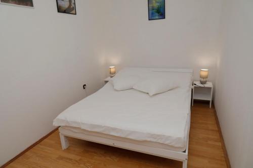 Una cama blanca con dos luces encima. en Maple place, en Velika Gorica