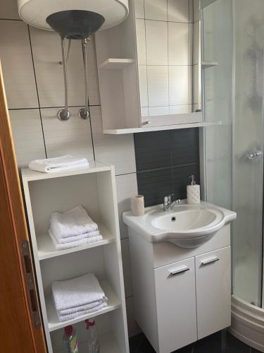 a white bathroom with a sink and a mirror at Guesthouse Villa Jurišić in Novalja