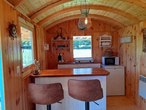 a kitchen with a counter and two chairs in a tiny house at La roulotte du pêcheur in Saint-Privé