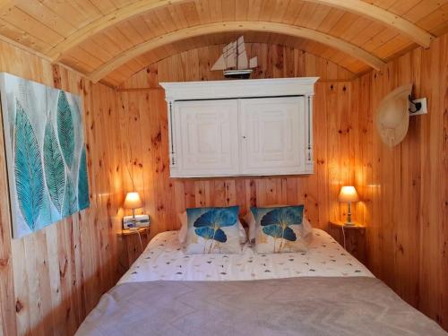 a bedroom with a bed in a wooden wall at La roulotte du pêcheur in Saint-Privé